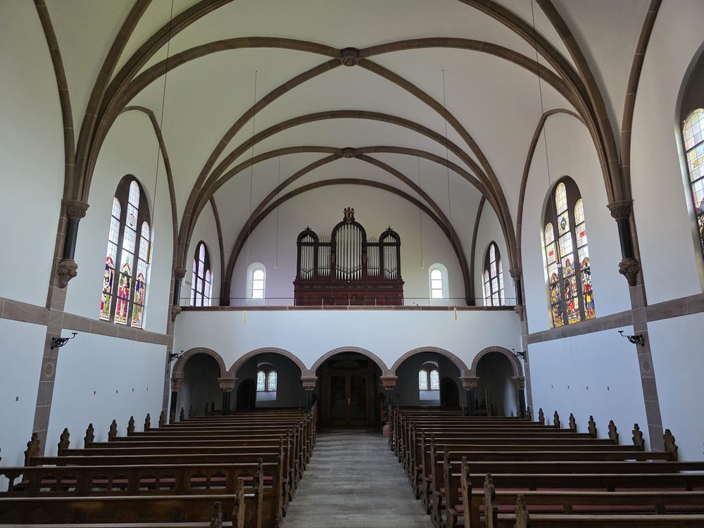 Blick zur Orgelempore – Kirchenschiff mit hellen Wänden und Kreuzgewölbe